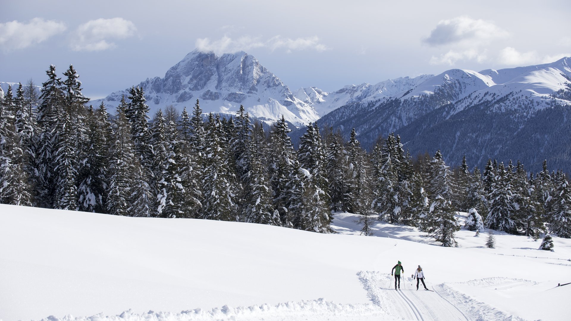 La pista di fondo sull’Alpe di Rodengo e Luson Due sciatori di fondo su pista innevata con montagne e foresta