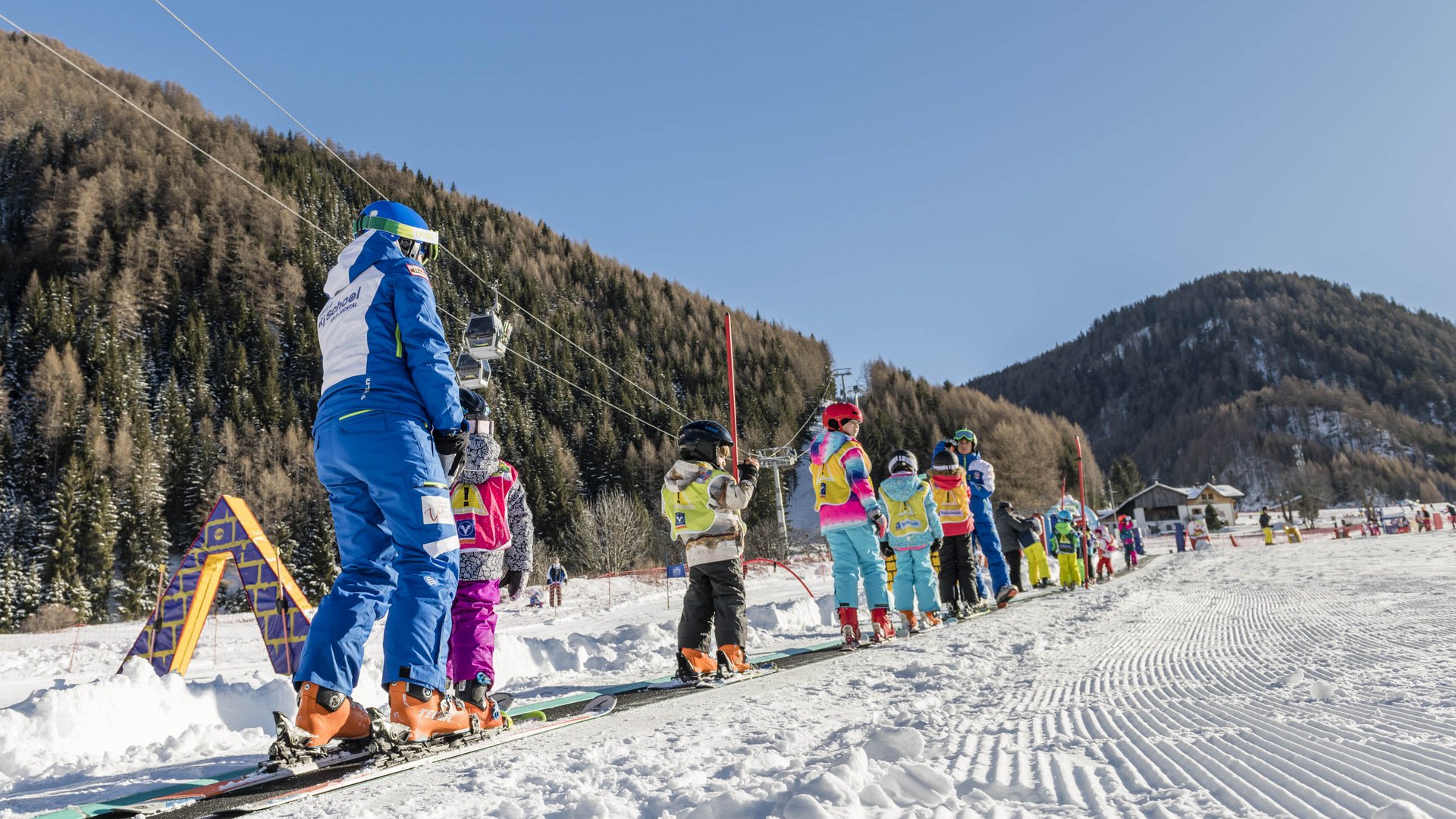 Valles & il villaggio alpino più bello dell’Alto Adige Bambini sciatori e istruttore sulla teleferica in una giornata di sole