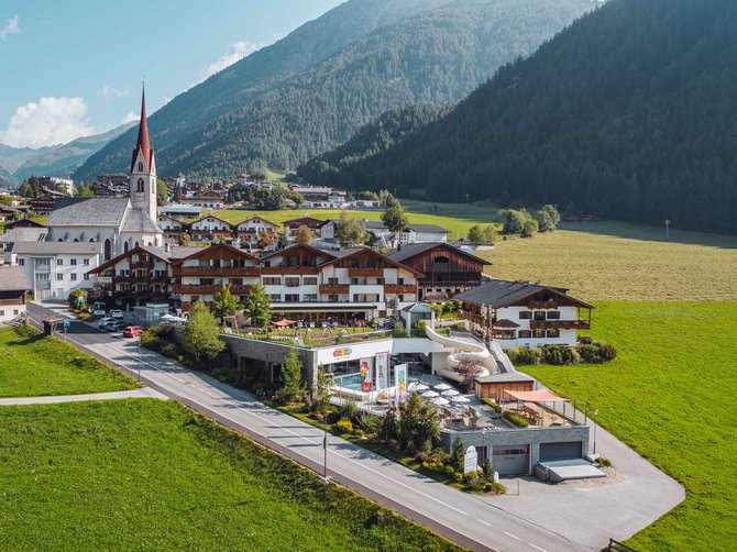Benvenuti nell’Area Vacanze Sci e Malghe Rio Pusteria! Vista di un villaggio con chiesa e montagne soleggiate sullo sfondo