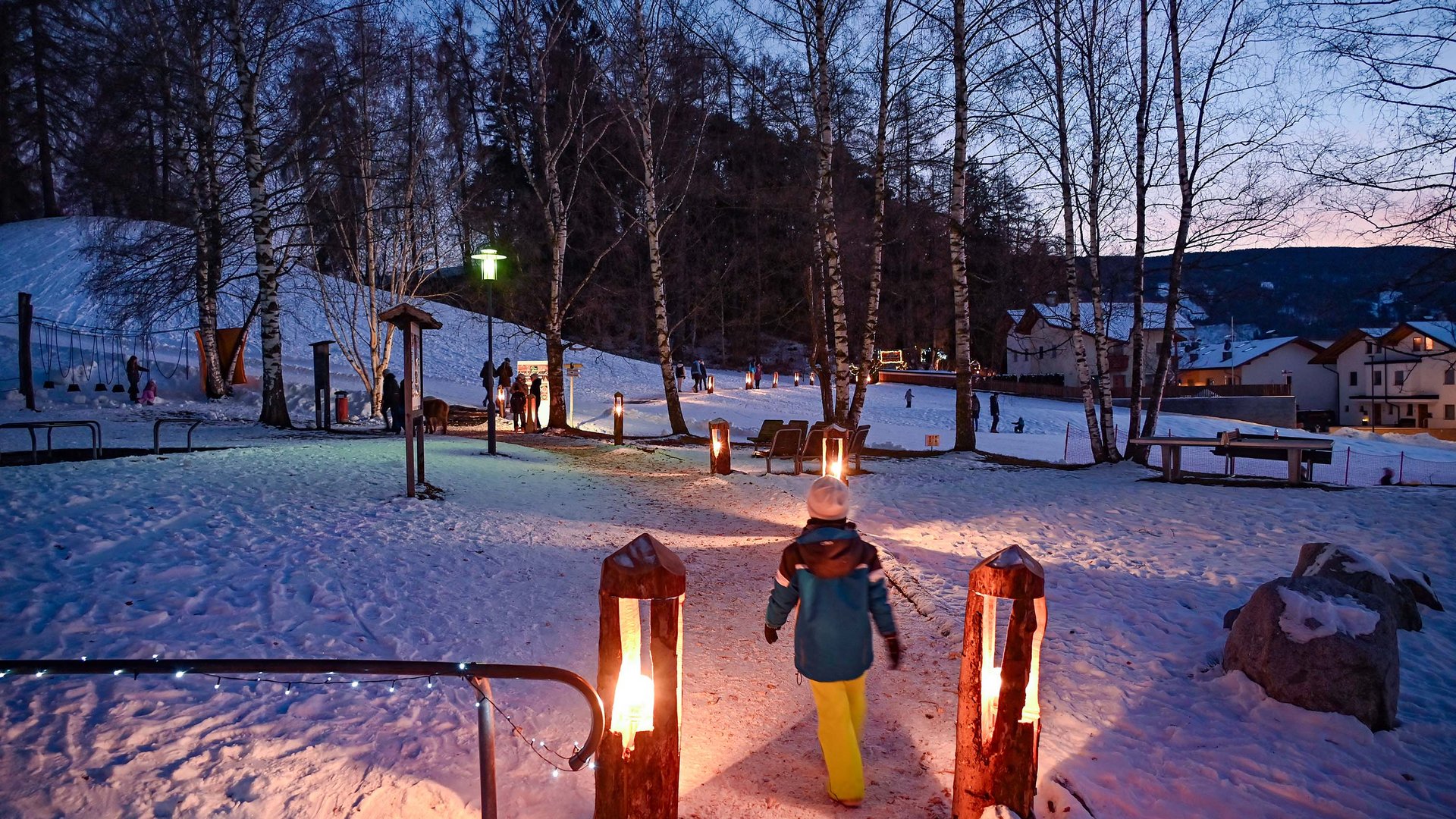 L’Avvento di Terento Bambino che cammina su un sentiero innevato illuminato di sera in un parco