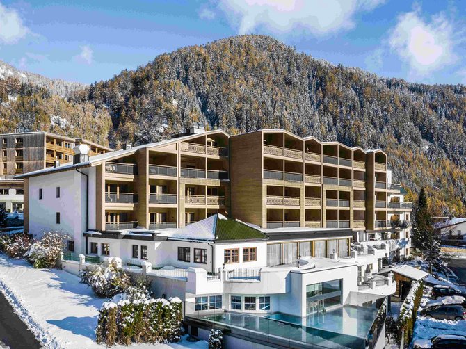 Benvenuti nell’Area Vacanze Sci e Malghe Rio Pusteria! Hotel moderno in paesaggio montano innevato con foresta sullo sfondo