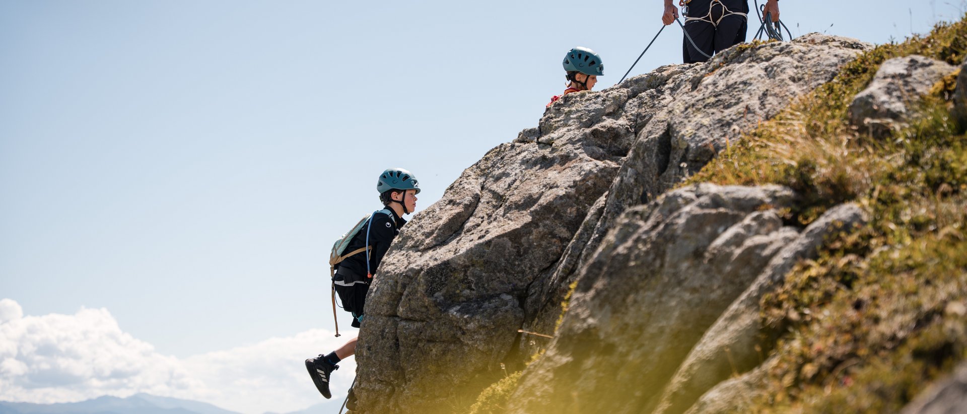 Vacanze in famiglia in Val Pusteria Bambini arrampicano su rocce con caschi e imbracature in montagna