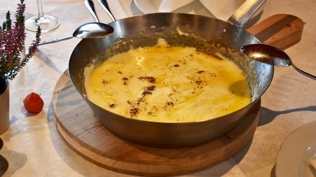 Vacanze sostenibili in Alto Adige Ciotola con formaggio fuso su tagliere di legno