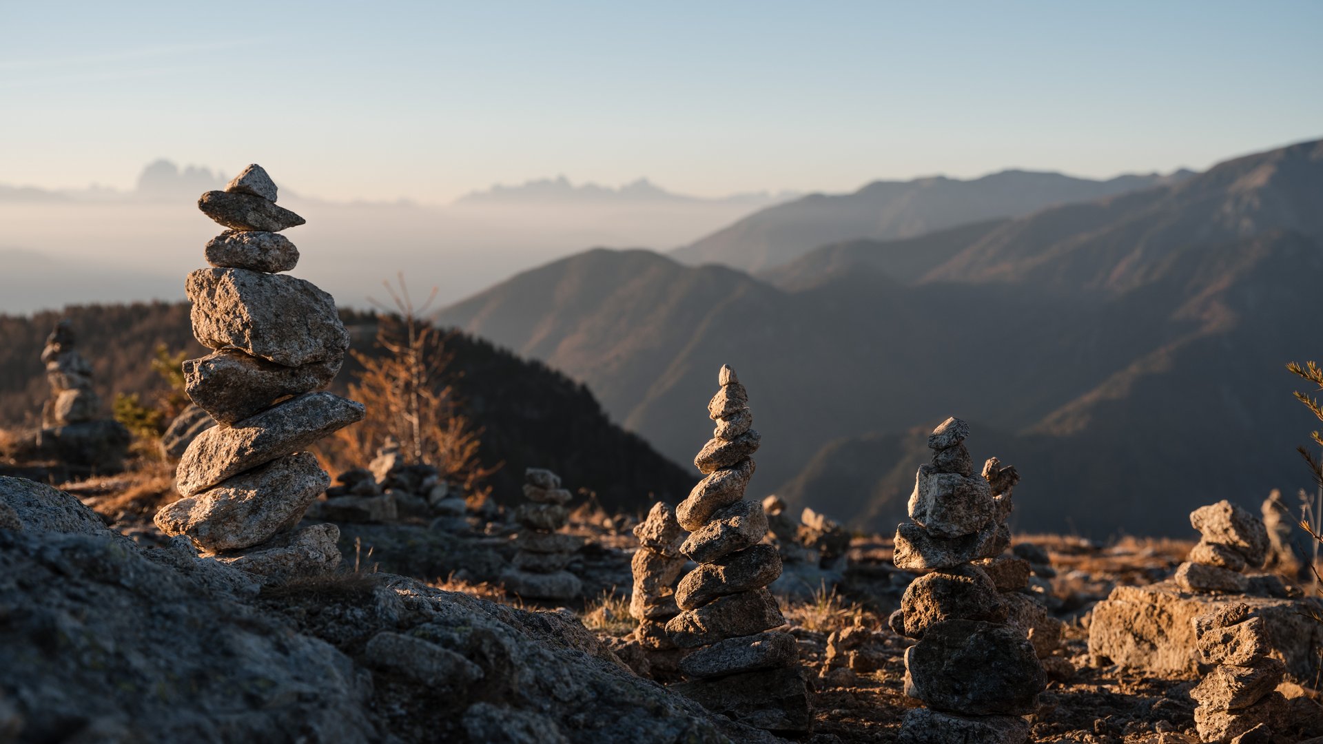 Vacanze sostenibili in Alto Adige Numerose pile di pietre su una montagna al sorgere del sole con sfondo sfocato