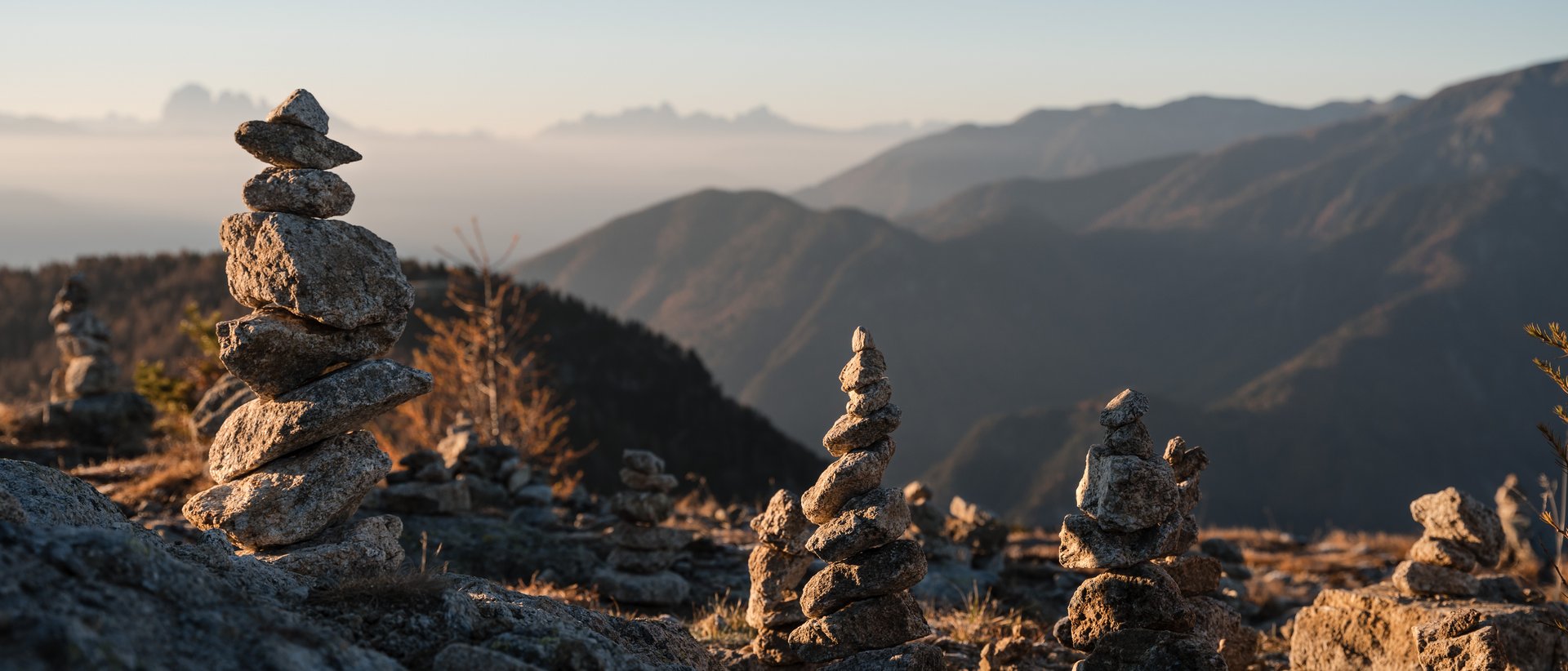 Almencard: la carta che apre tutte le porte Numerose pile di pietre su una montagna al sorgere del sole con sfondo sfocato