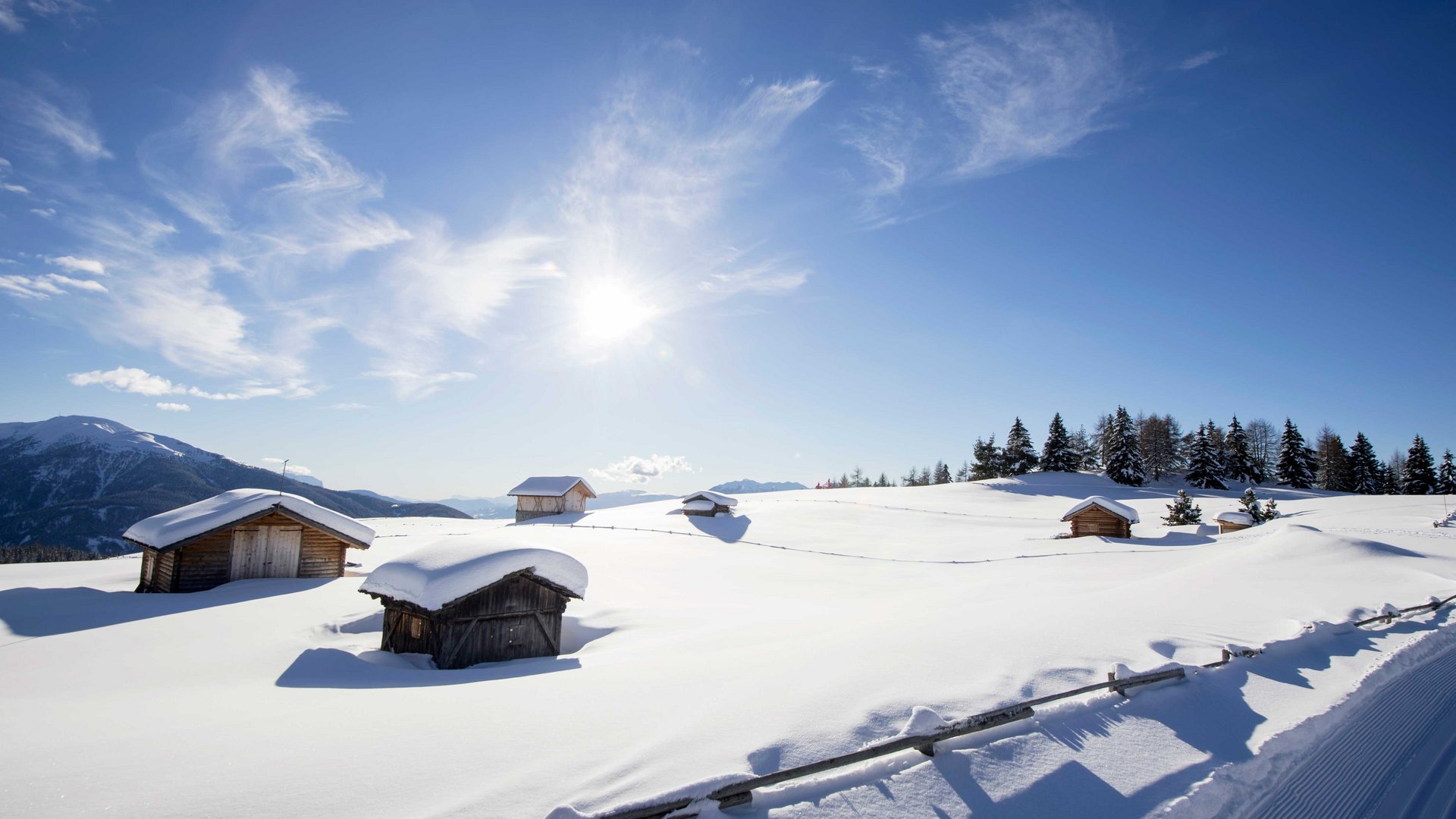La pista di fondo sull’Alpe di Rodengo e Luson Baite di legno innevate su montagna soleggiata con cielo azzurro