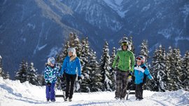 Voglia di slittino? Venite a Terento! Famiglia cammina con slittini in montagna innevata