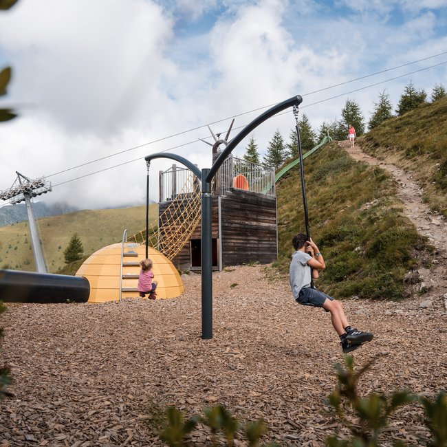 Sapori in malga Bambini che giocano su scivolo a fune in parco giochi di montagna