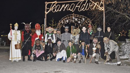 Vacanze sostenibili in Alto Adige Persone in costumi tradizionali di Krampus e San Nicola davanti all'arco luminoso