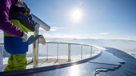 La piattaforma panoramica Gitschberga a Maranza (BZ) Persone che osservano un paesaggio montano innevato con un telescopio sotto il sole