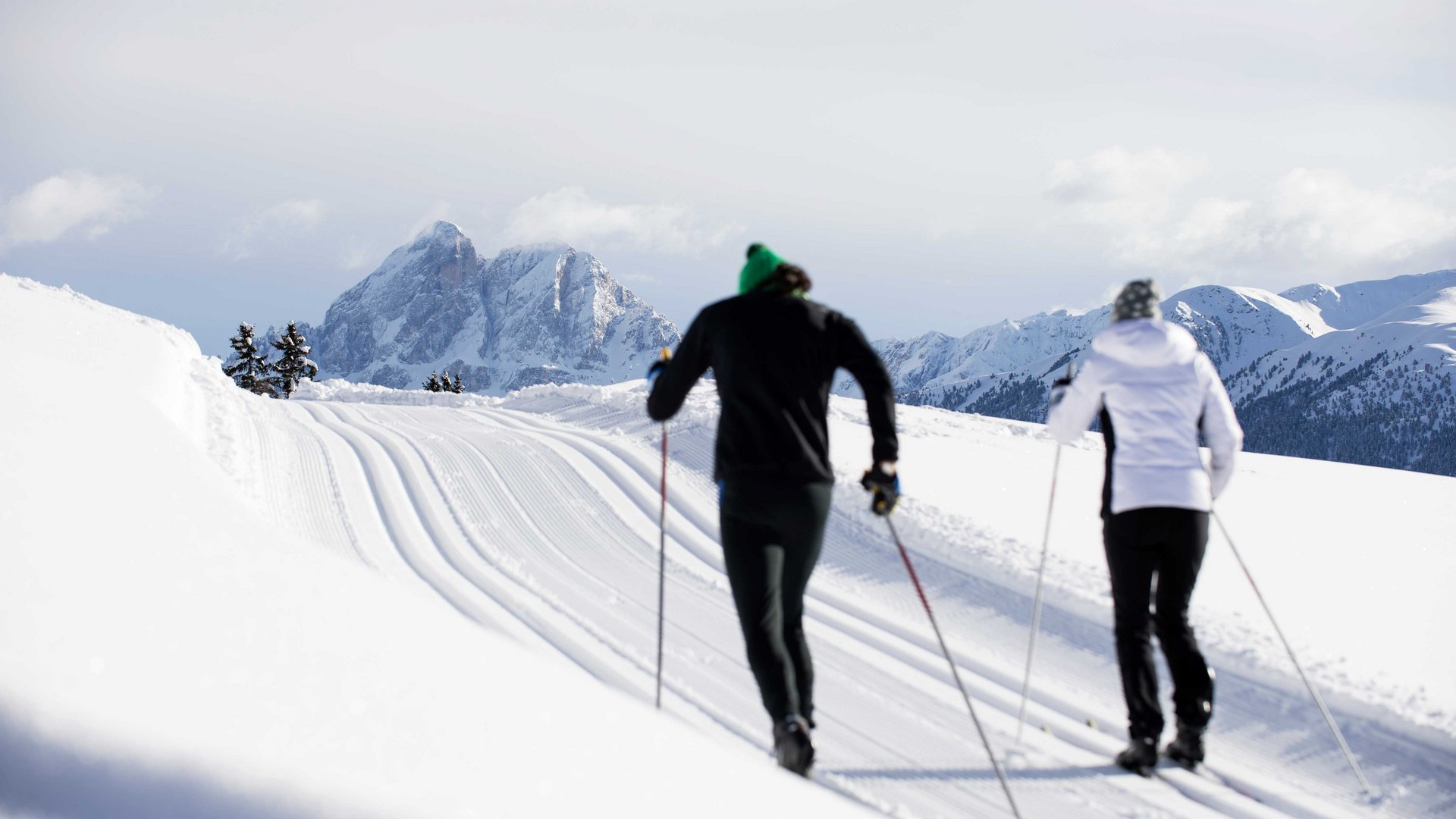 L’Alpe di Rodengo e Luson Due sciatori su pista innevata con montagne sullo sfondo