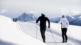 L’Alpe di Rodengo e Luson Due sciatori su pista innevata con montagne sullo sfondo