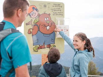 Outdoor Escape sul Monte Gitschberg Famiglia legge cartello informativo per caccia ai ladri sul Gitschberg
