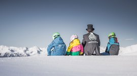 Sciare in Alto Adige: Rio Pusteria Tre bambini e un adulto seduti sulla neve con vista sulle montagne