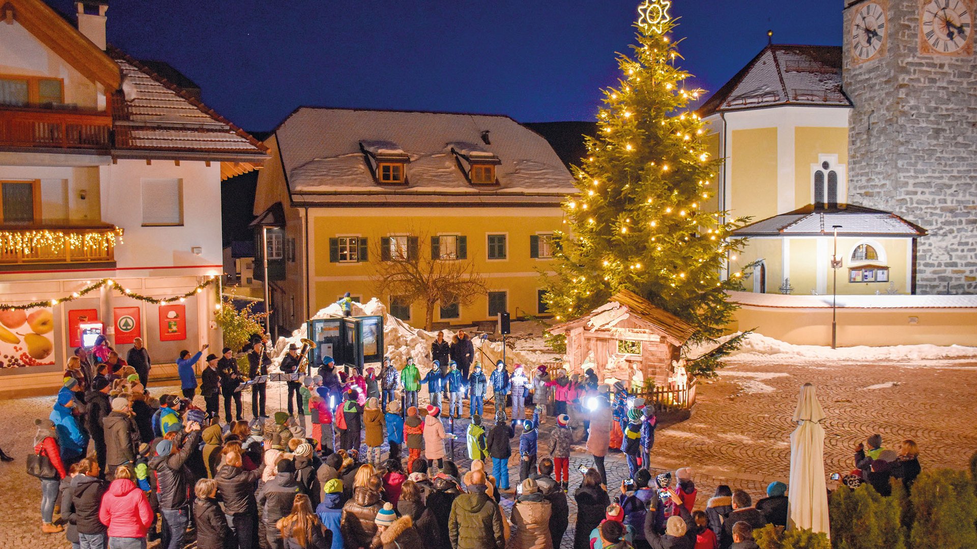 L’Avvento di Terento Albero di Natale illuminato con persone che partecipano a una festa in piazza
