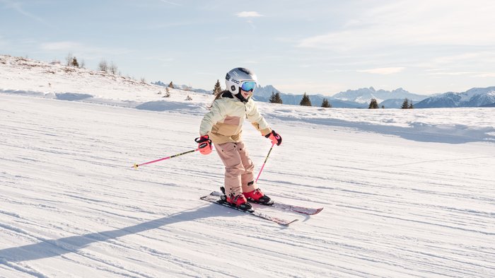 Settimane bianche in Alto Adige Bambino scia su pista innevata con montagne sullo sfondo