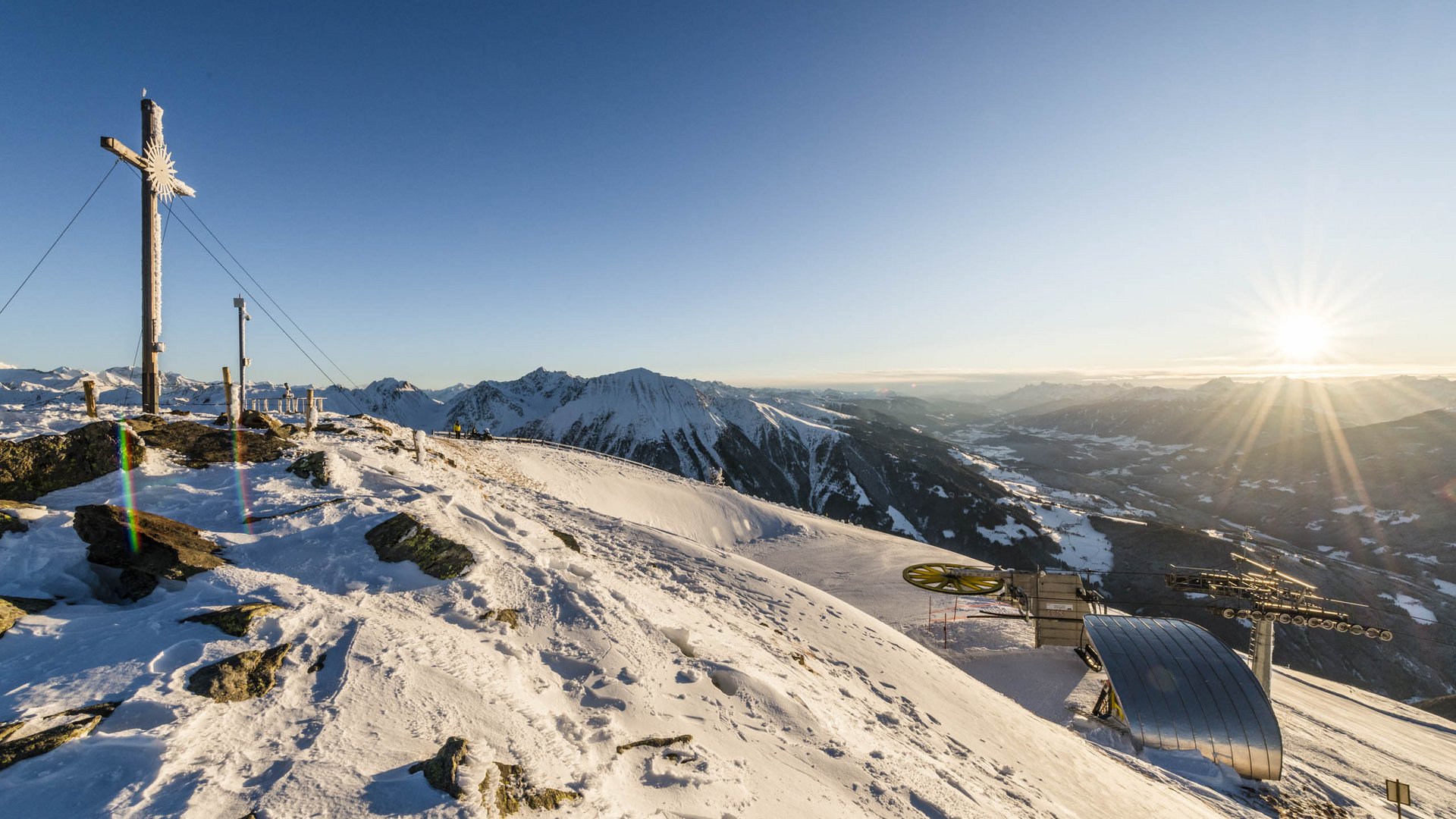 La piattaforma panoramica Gitschberga a Maranza (BZ) Tramonto su montagna innevata con croce e impianto di risalita