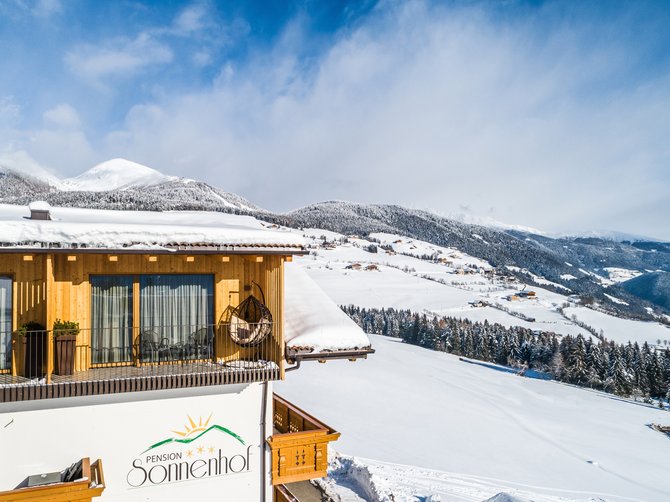 Benvenuti nell’Area Vacanze Sci e Malghe Rio Pusteria! La pensione "Sonnenhof" con un paesaggio innevato e montagne coperte di neve sullo sfondo