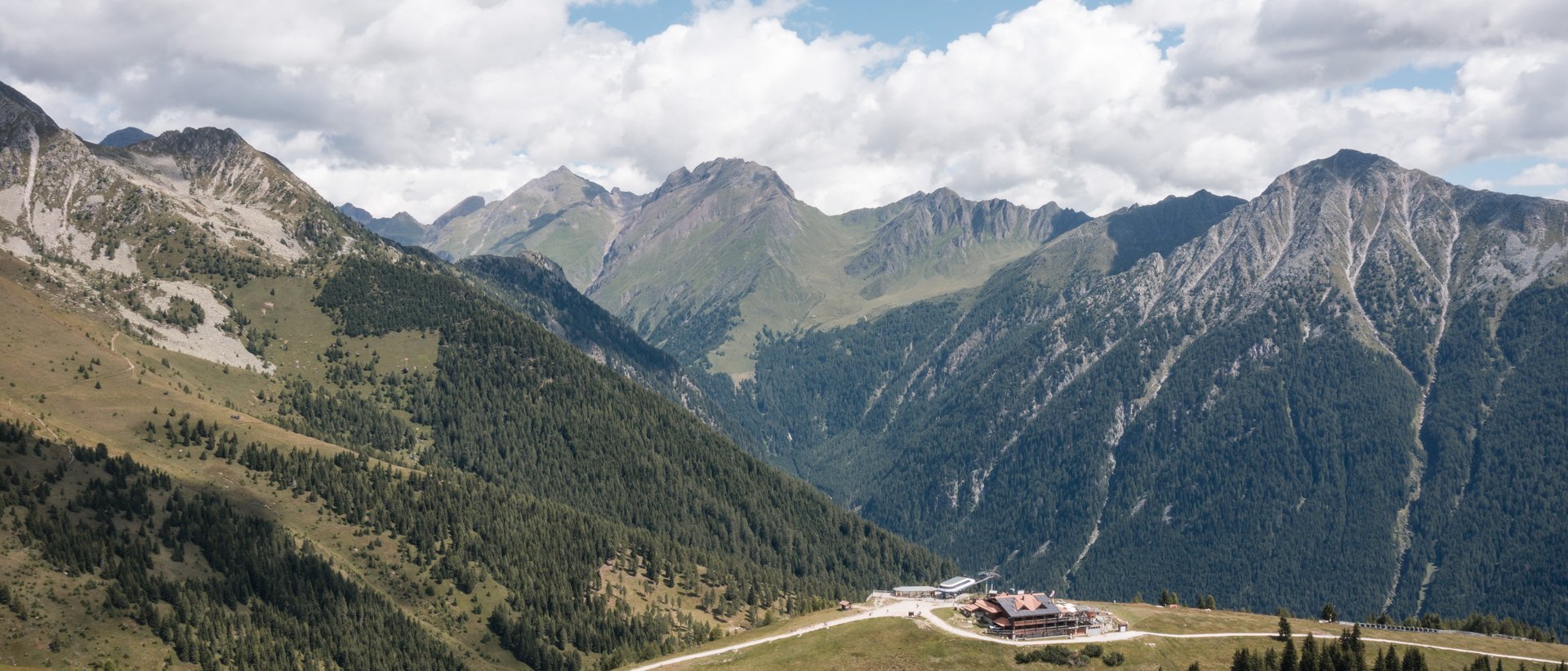 Almencard: la carta che apre tutte le porte Paesaggio montano con pini, edificio e cielo nuvoloso