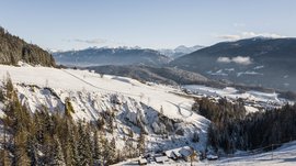 Terento in Val Pusteria Paesaggio alpino innevato con case e foresta sotto un cielo sereno