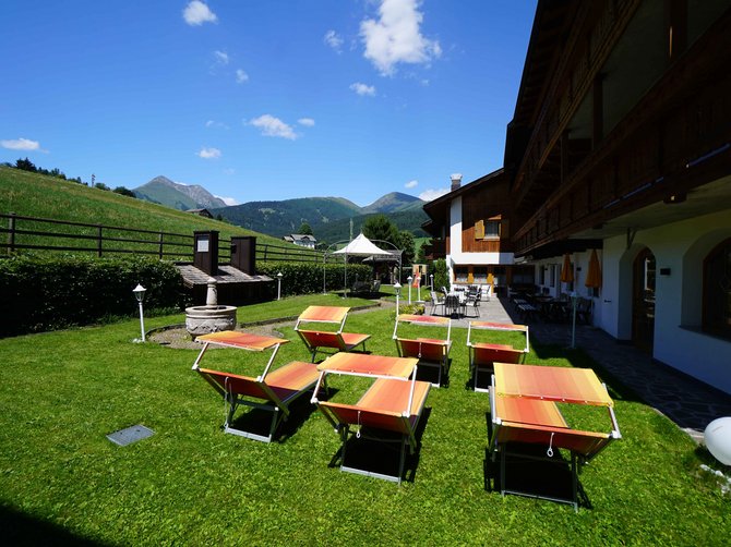 Benvenuti nell’Area Vacanze Sci e Malghe Rio Pusteria! Giardino con sdraio davanti a un hotel alpino in una giornata soleggiata