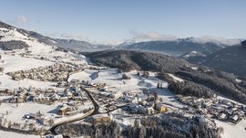 Le piste di fondo a Terento Paesaggio invernale con villaggio innevato in una valle e montagne sullo sfondo