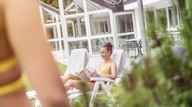 La piscina Alpinpool a Maranza Una giovane donna in bikini giallo su una sdraio che legge una rivista