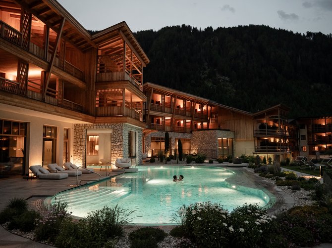 Benvenuti nell’Area Vacanze Sci e Malghe Rio Pusteria! Hotel illuminato con piscina esterna e due persone in acqua di notte