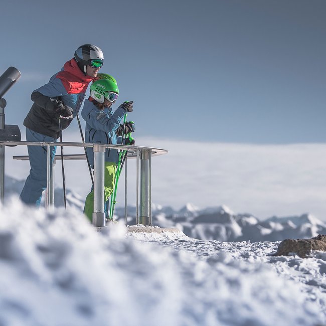 Trovate il vostro hotel in Val Pusteria Due sciatori in piedi su una piattaforma panoramica sulla neve