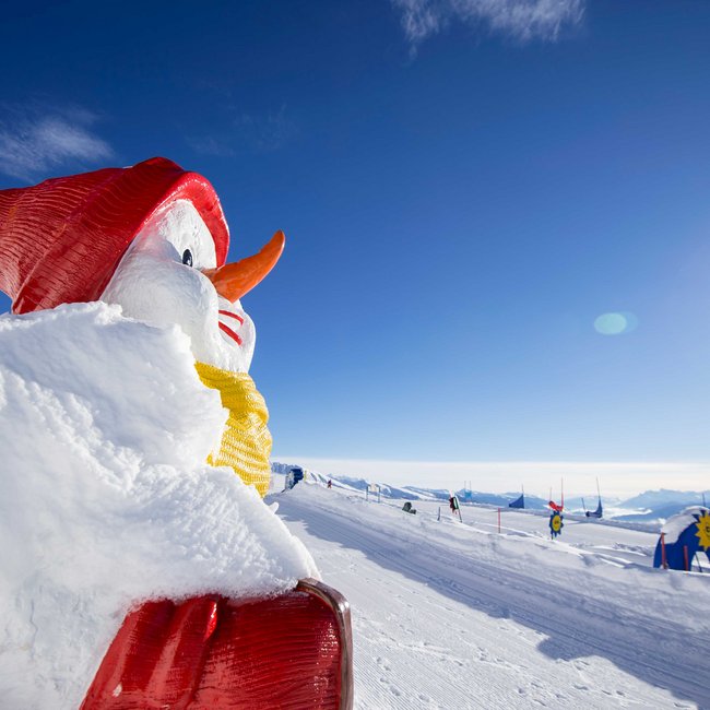Rio Pusteria: il comprensorio sciistico per famiglie in Alto Adige Grande pupazzo di neve con cappello rosso e sciarpa su collina innevata