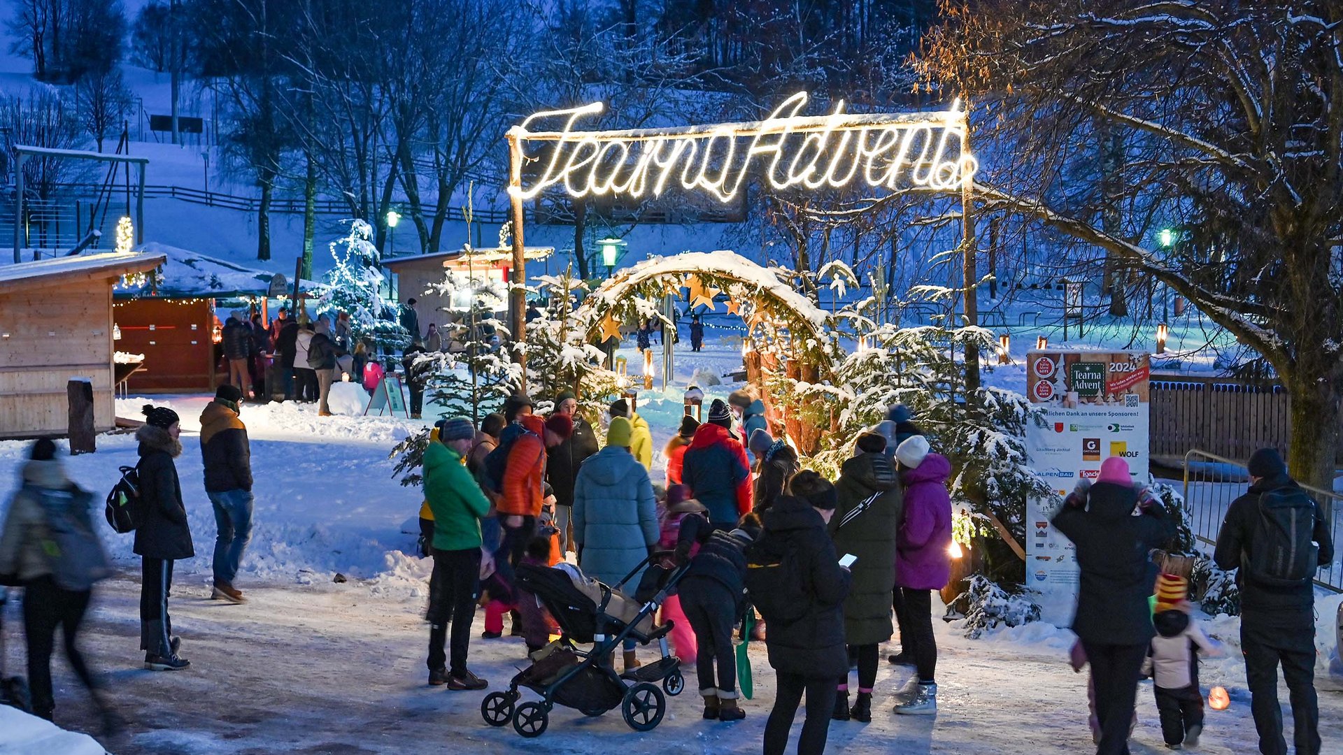 L’Avvento di Terento Persone che visitano un mercato natalizio di Avvento sotto la neve di sera