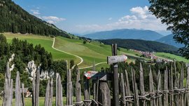 Le piramidi di terra di Terento Recinzione di legno con cartelli escursionistici su colline verdi e montagne
