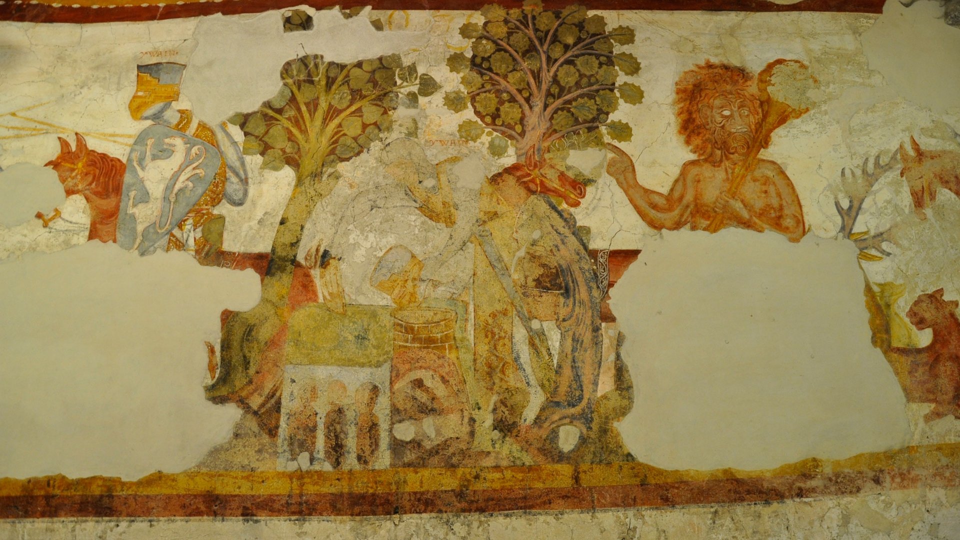 Alla scoperta di Castel Rodengo L'immagine mostra un antico affresco murale parzialmente danneggiato. Raffigura una scena con un cavaliere in armatura, un albero e una figura mitologica con capelli rossi. I colori sono sbiaditi e alcune parti dell'affresco mancano.