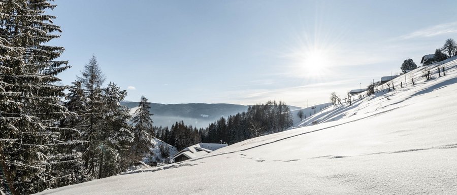 Le località dell’area vacanze Rio Pusteria Paesaggio invernale innevato con alberi e case sotto il sole