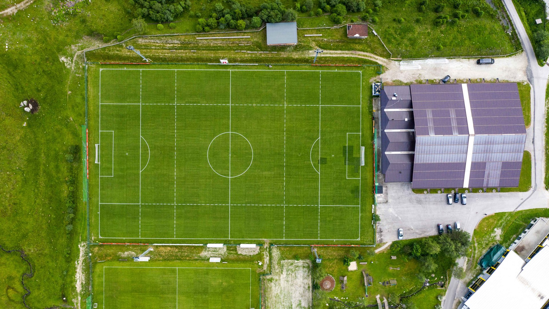 Ritiro Bologna FC 1909 Si vedono due campi da calcio dall'alto. Uno grande e uno piccolo. Intorno ai campi c'è un'area verde.