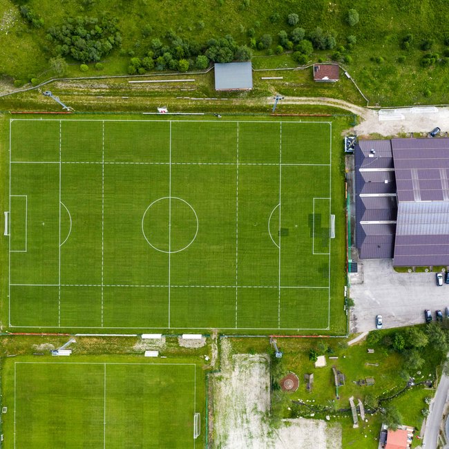 Vacanze estive in Alto Adige: escursioni e altre attività Si vedono due campi da calcio dall'alto. Uno grande e uno piccolo. Intorno ai campi c'è un'area verde.
