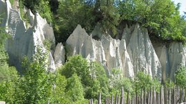 Le piramidi di terra di Terento Formazioni rocciose con recinzione di pali di legno e alberi verdi al sole