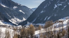 Quando si dice idilliaco… ecco a voi Fundres L'immagine mostra una valle innevata con montagne sullo sfondo. Al centro dell'immagine c'è un villaggio, parzialmente circondato da foreste. Una chiesa con una torre distintiva è ben visibile nel centro del villaggio.