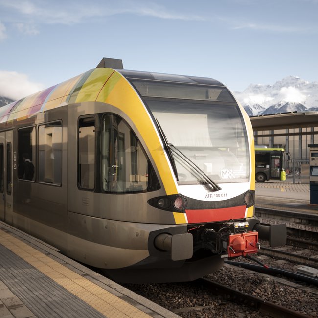 Vacanze sostenibili in Alto Adige Treno moderno alla stazione con montagne innevate sullo sfondo