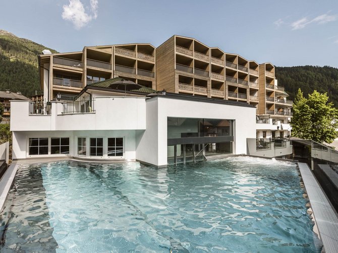 Benvenuti nell’Area Vacanze Sci e Malghe Rio Pusteria! Piscina esterna con vista su edificio moderno e montagne